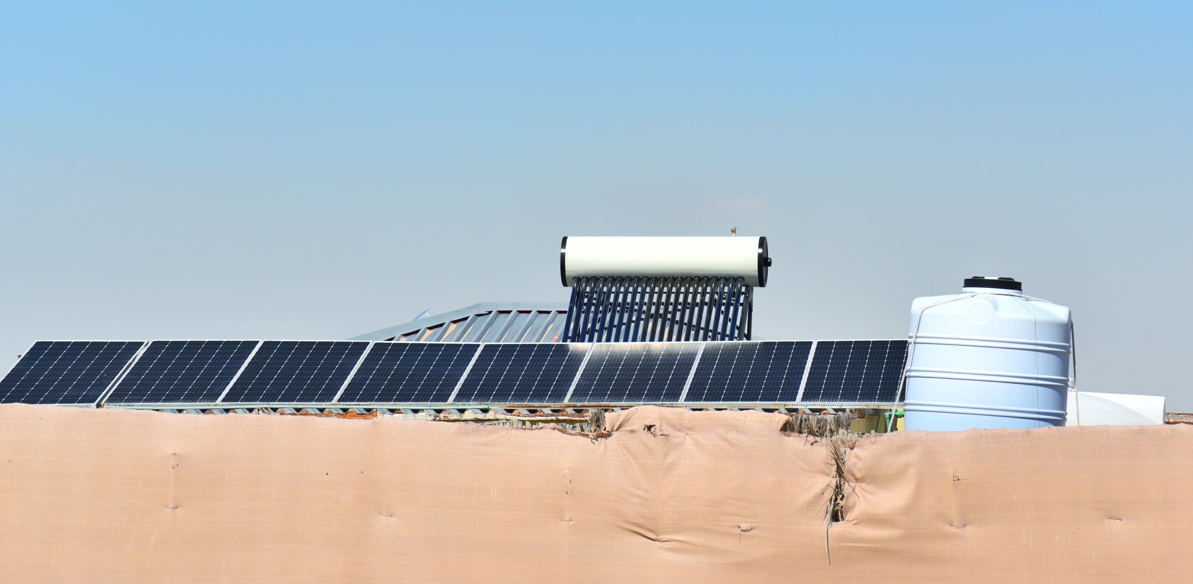 Solaranlage mit Wasserboiler und Wassertank auf einem Flachdach – Teil eines ganzheitlichen Versorgungsprojekts, das durch den Verkauf modularer Designmöbel von MALYA ermöglicht wird, um Strom und sauberes Wasser in abgelegene Regionen zu bringen.
