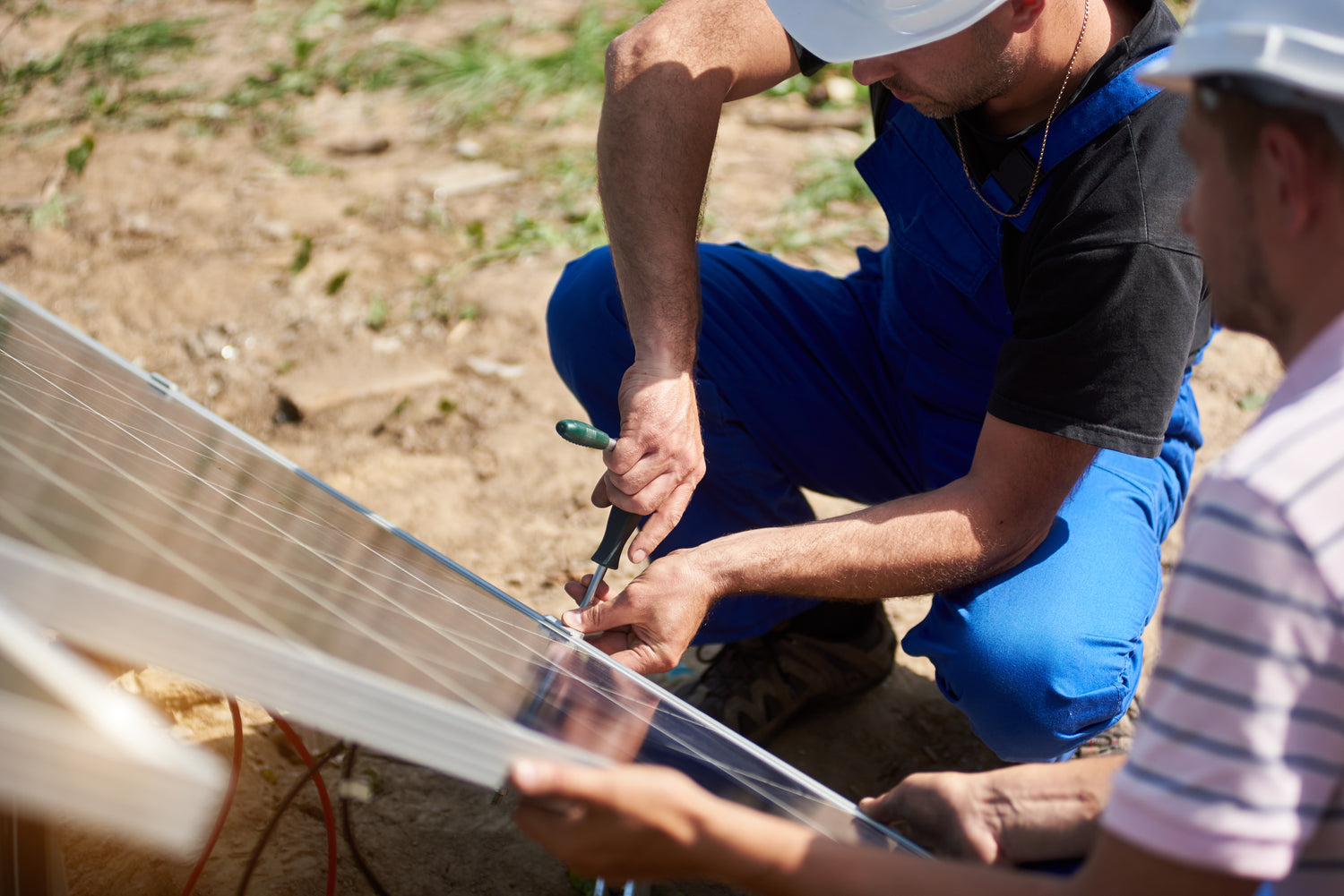Zwei Techniker montieren ein Solarpanel – Aufbau eines durch MALYA finanzierten Photovoltaiksystems zur nachhaltigen Stromversorgung ländlicher Regionen, realisiert durch Spenden aus dem Verkauf modularer Möbel wie MALYA Regale, Betten und Garderoben.